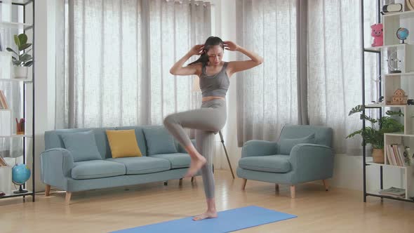 Athletic Female Doing Cardio High Knees And Squat Exercises During Daily Workout On The Mat At Home