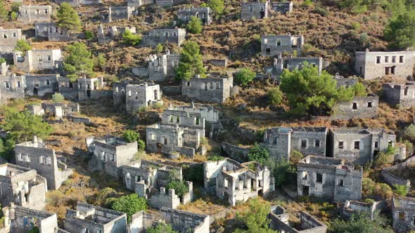 aerial drone panning up showing the abandoned buildings and homes left in ruins on the mountain of K
