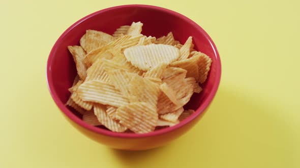 Close up of potato chips in a bowl with copy space on yellow surface