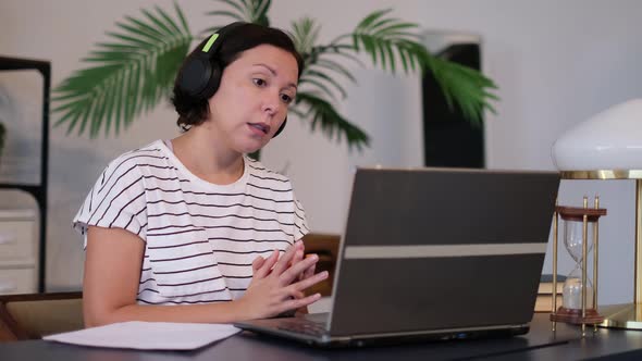 Young Woman Wears Headset Conference Calling on Laptop Talks with Online Teacher Studying Working