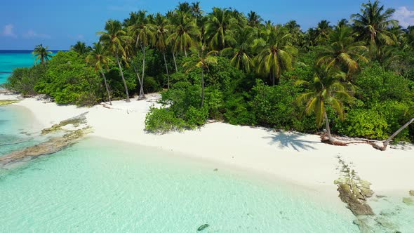 Daytime fly over travel shot of a sandy white paradise beach and aqua turquoise water background in 