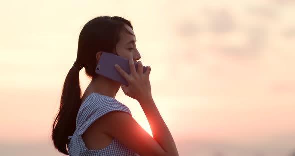 Woman talk to cellphone under sunlight