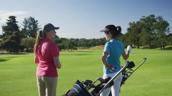 Two caucasian female golf players talking standing on golf field