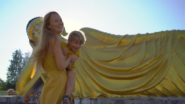 Slowmotion Shot of a Young Woman and Her Little Son Having Fun in Front of a Statue of the Lying