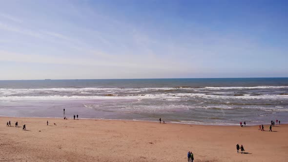 People Walking On Katwijk aan Zee Beach With Waves. Aerial Pedestal Up, Dolly Forward