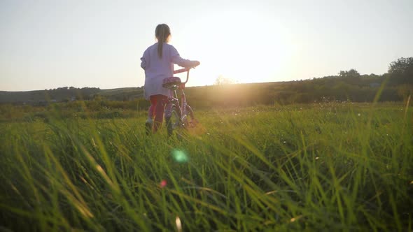 Biker Child Enjoying Freedom on Bike at Sunset. Girl on a Bike in the Countryside in Sunset Time.