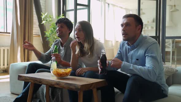 Funny Friends Celebrate the Victory of Their Favorite Team Sitting on the Couch