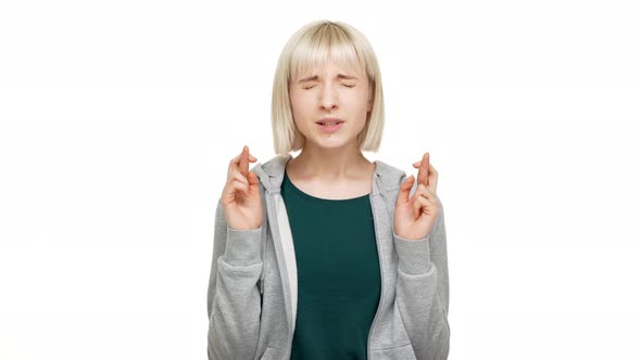 Portrait of 20s Blond Woman Wearing Sweatshirt Wishing for Good Luck Looking Up with Closed Eyes and