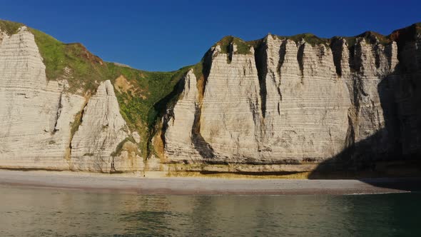 Picturesque Striped Rocks with Green Grass on Top Stretch Along the Sea Coast