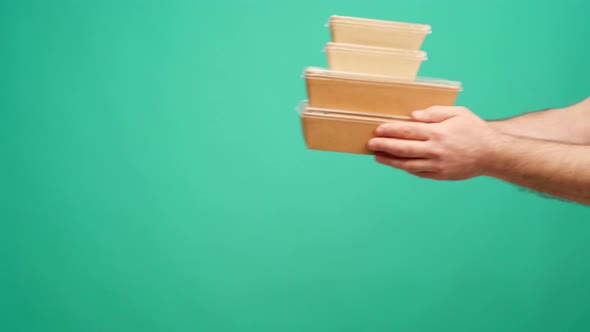 People's Hands Passing Each Other Packed Boxes with Food Delivery Against Mint Studio Background