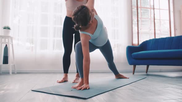 Pregnant woman doing yoga exercise with personal trainer at home.