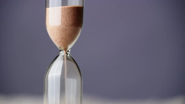 Countdown Hourglass Pouring on Purple Background