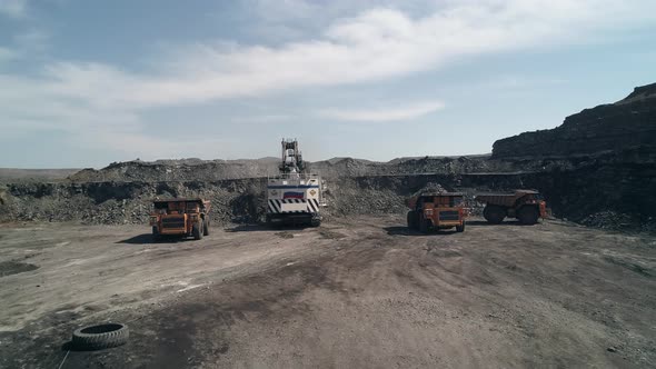 Group of Technological Transport Around Huge Mining Excavator