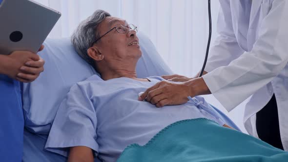 Doctor listening to patient's heart rate with stethoscope on hospital bed