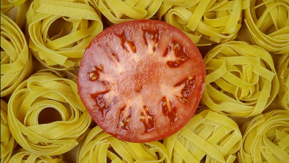 Lots of Dry Tagliatelle Pasta Garnished with Cut Tomato in Center of Circle Rotate Clockwise