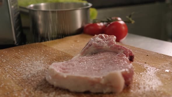 A Male Chef Salts a Pork Steak in a Professional Kitchen in a Restaurant