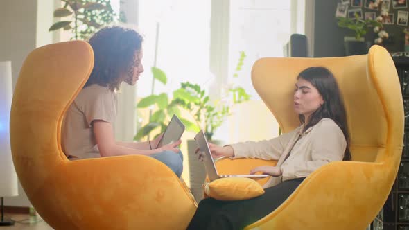 Diverse Multiethnic Couple Sitting on Couch Sofa in Stylish Living Room and Choosing Items Buy