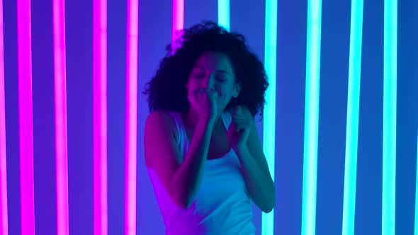 African American Woman Dancing in the Studio Against a Background of Blue and Pink Neon Lights