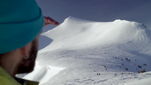 Man Hiker Rising hand and Overlooking Mountain With Glacier in Winter