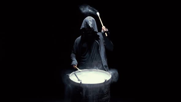 Hooded Man Beats Drum with Flour