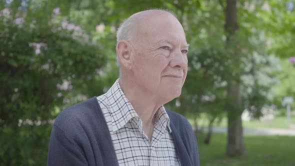 Portrait of Cute Old Man Sitting on a Bench in the Park. Adorable Mature Grandfather Resting