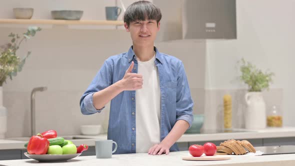 Young Asian Man Showing Thumbs Up While Standing in Kitchen