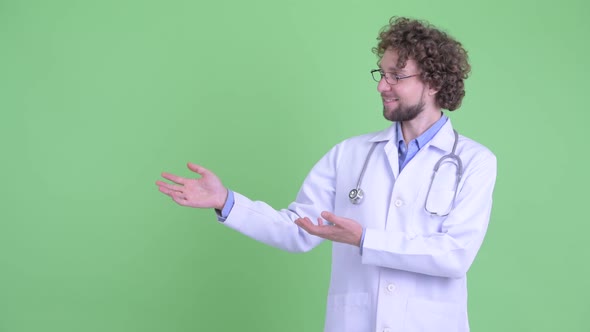 Happy Young Bearded Man Doctor Showing Something and Giving Thumbs Up