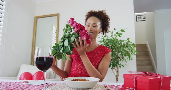 Happy mixed race woman on a valentines date video call, holding flowers