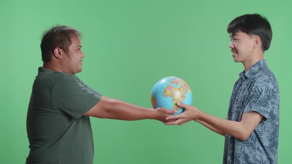 Man Hand In The World Globe To Young Man While Standing In Front Of Green Screen Background