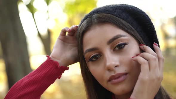 Close Portrait of Girl in a Cap Posing and Flirting at Camera in a Park