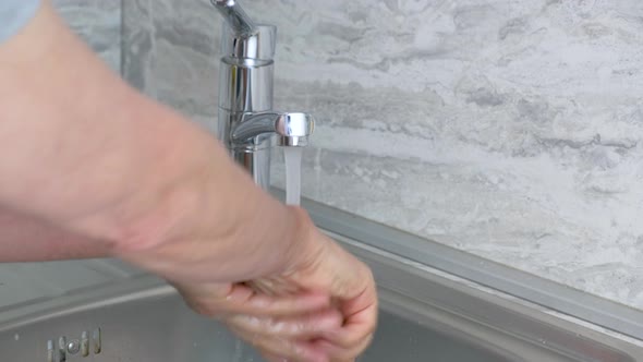 Man Washes His Hands with Soap Under the Streem at Home