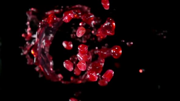 Pomegranate Grains are Bouncing Up with Splashes of Juice on a Black Background