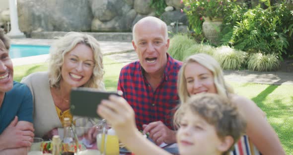 Happy caucasian family having dinner and taking selfie in garden