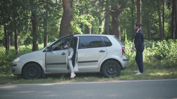 Wide Shot Woman Walking Out Driver's Seat Helping Man Pushing Vehicle on Suburban Roadside on Sunny