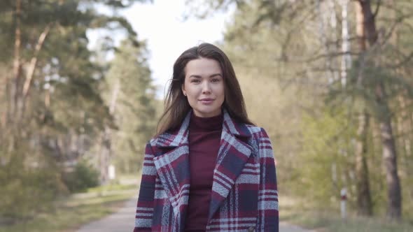 Portrait of Confident Brunette Girl Walking To Camera Along Empty Small Road. Positive Brown-eyed