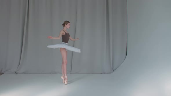 A Young Promising Ballerina Is Dancing a Classical Ballet. White Background and Bright Lighting in