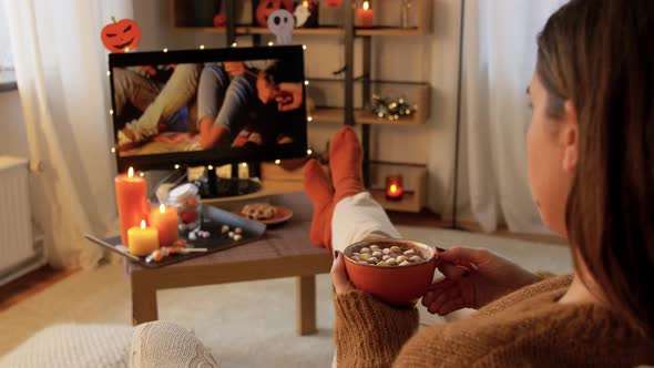 Woman Watches Tv and Drinks Cocoa on Halloween