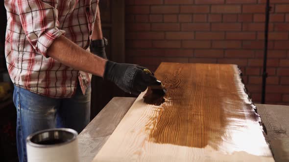 Close Up Shot of a Man's Hands, Who Paints a Wooden Table with Lacquer