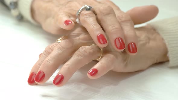 Elderly Woman Hands with Red Manicure.