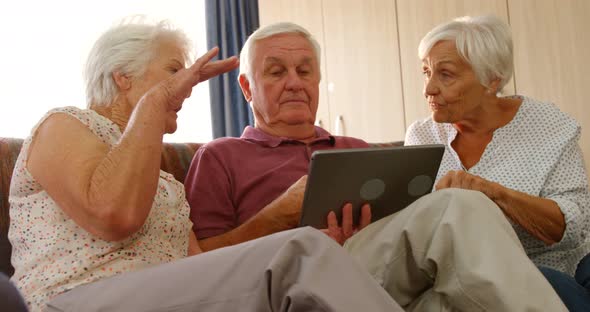 Senior friends discussing together with a digital tablet