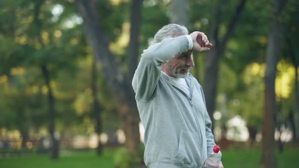 Athlete Pensioner Wiping Sweat Drinking Water After Outside Training, Fitness