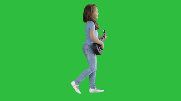 Cute little girl walking and singing while playing on ukulele