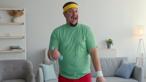 Expressive Funny Overweight Man in Bright Sport Clothes Exercising with Dumbbells Looking Excited