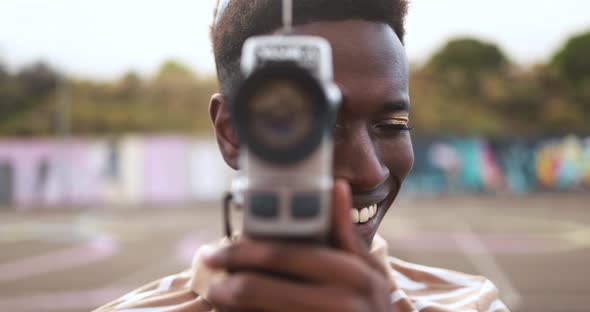 Young african man using vintage old video camera outdoor