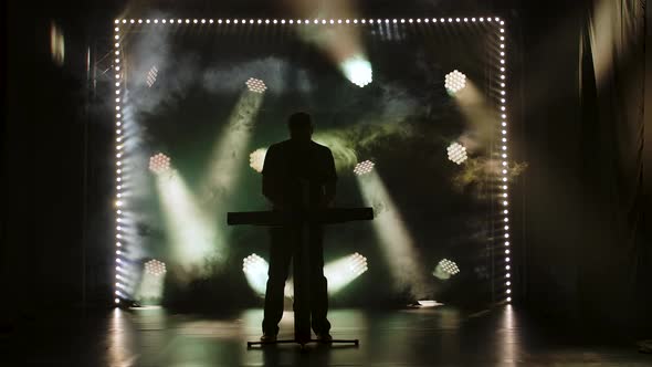 Musician Silhouette Playing on Synthesizer Piano Keyboard on Stage in a Dark Studio with Smoke and