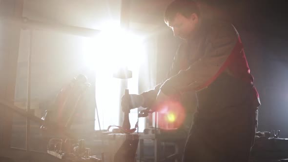 Man Blacksmith Bending Hot Piece of Metal Using a Form on an Anvil and Hitting the Detail with a