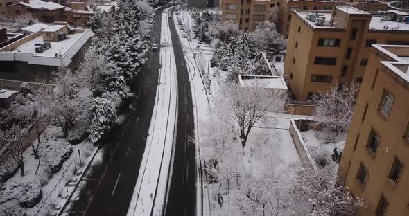 Flying slow like a bird on a snow covered street in winter in Tehran Iran. two line Blvd. urban buil