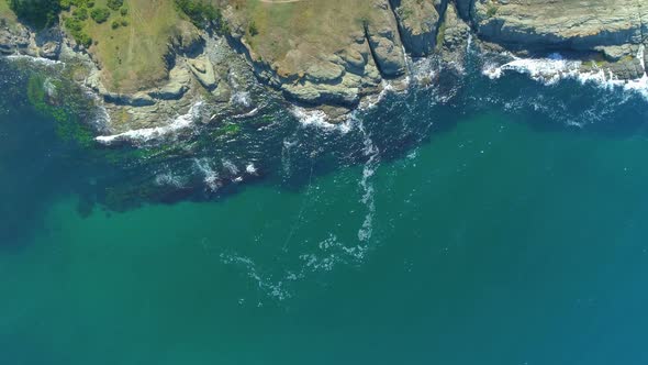 Clear Sea Water Waves Crashing at Rocks. Agricultural Fields at The Sea Coast