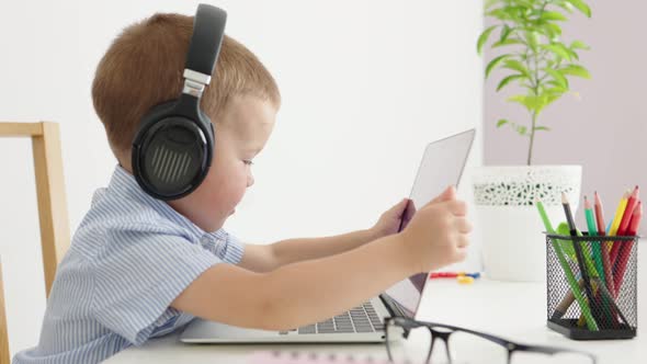 Caucasian Baby Kid Child Boy in Headphones Opening Laptop Starting Type Keyboard