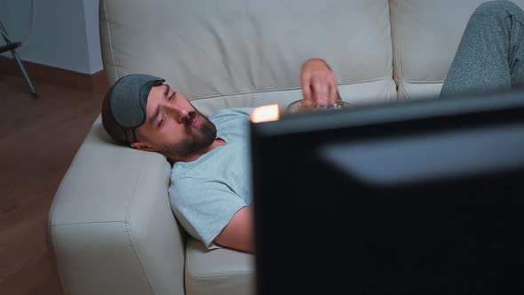 Caucasian Male with Eye Sleep Mask Eating Popcorn While Watching Entertainment Tv Show